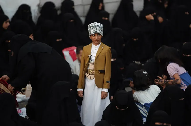Di Yaman, seorang anak laki-laki mengenakan pakaian tradisional tampak berdiri di tengah kerumunan warga yang menunggu pelaksanaan salat Idul Adha di Lapangan Kebebasan, Taiz.
