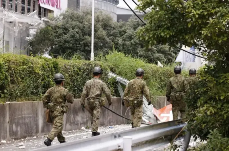 Para petugas penyelamat berjalan menuju gedung Aeon Mall Kumamoto yang rusak parah di Kashima, Prefektur Kumamoto
