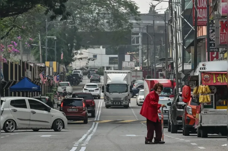 Seorang wanita yang mengenakan masker wajah berjalan di sepanjang jalan di Kuala Lumpur pada 19 Oktober 2026, saat Malaysia terus diselimuti kabut asap akibat kebakaran di Indonesia