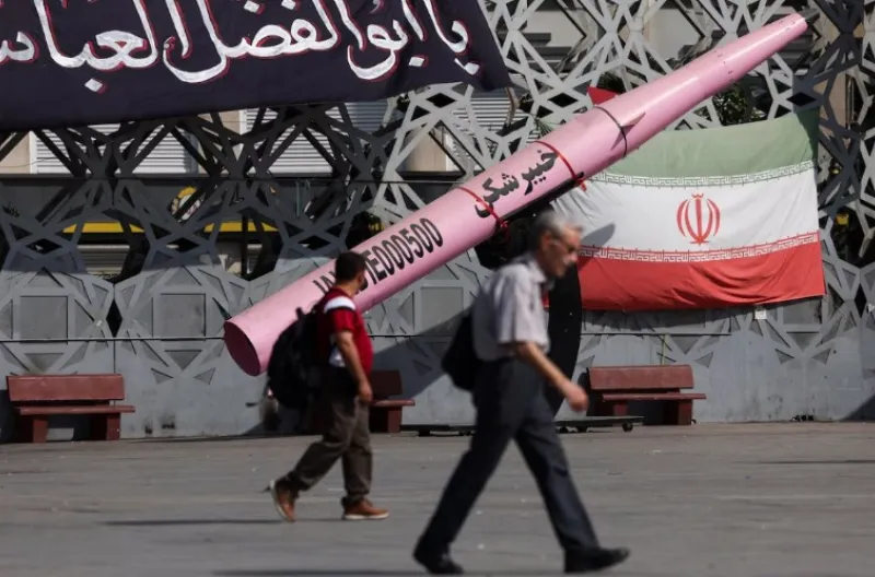 Orang-orang berjalan di samping maket simbolis rudal Iran dan bendera Iran di Lapangan Imam Hussein di Teheran, Iran