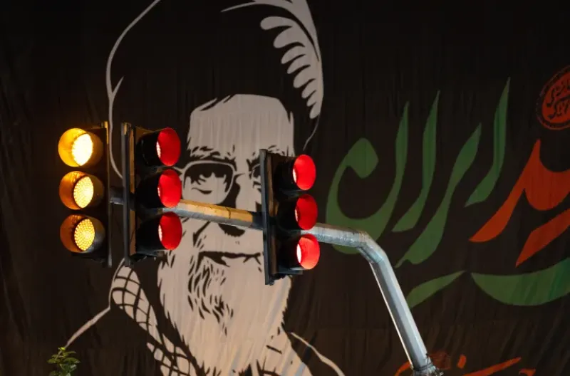 Lampu lalu lintas berkedip di dekat gambar besar yang menghormati mantan Pemimpin Tertinggi Iran Ayatollah Ali Khamenei, pada 3 Juli 2026, di Teheran, Iran
