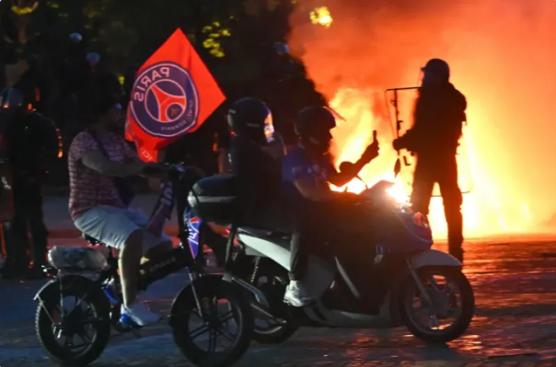 Suporter PSG mengendarai skuter mereka melewati polisi anti huru hara di Place du Trocadero di Paris