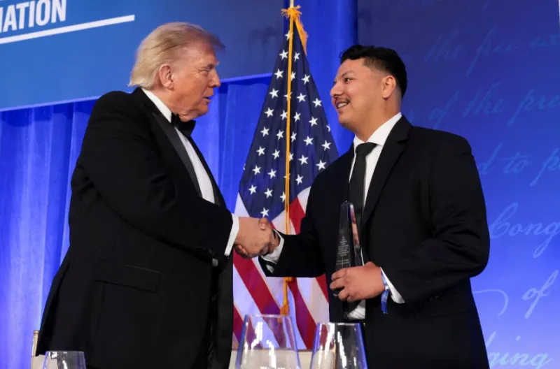 Presiden AS Donald Trump berjabat tangan dengan petugas Secret Service Victor Gonzales yang diberi penghargaan karena membantu menghentikan pria bersenjata setelah ia mencoba menerobos keamanan dan menembakkan senapan di acara makan malam White House Corr