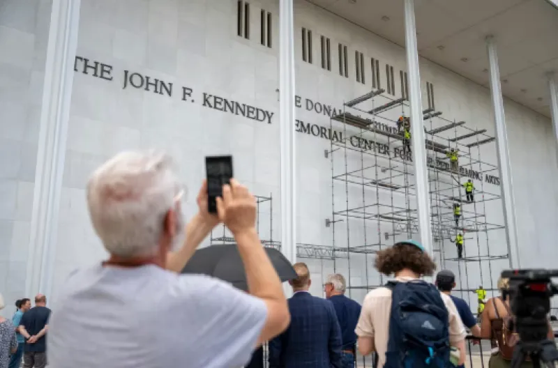 Orang-orang berhenti untuk menyaksikan para pekerja memasang perancah di Kennedy Center di Washington, DC, pada hari Jumat